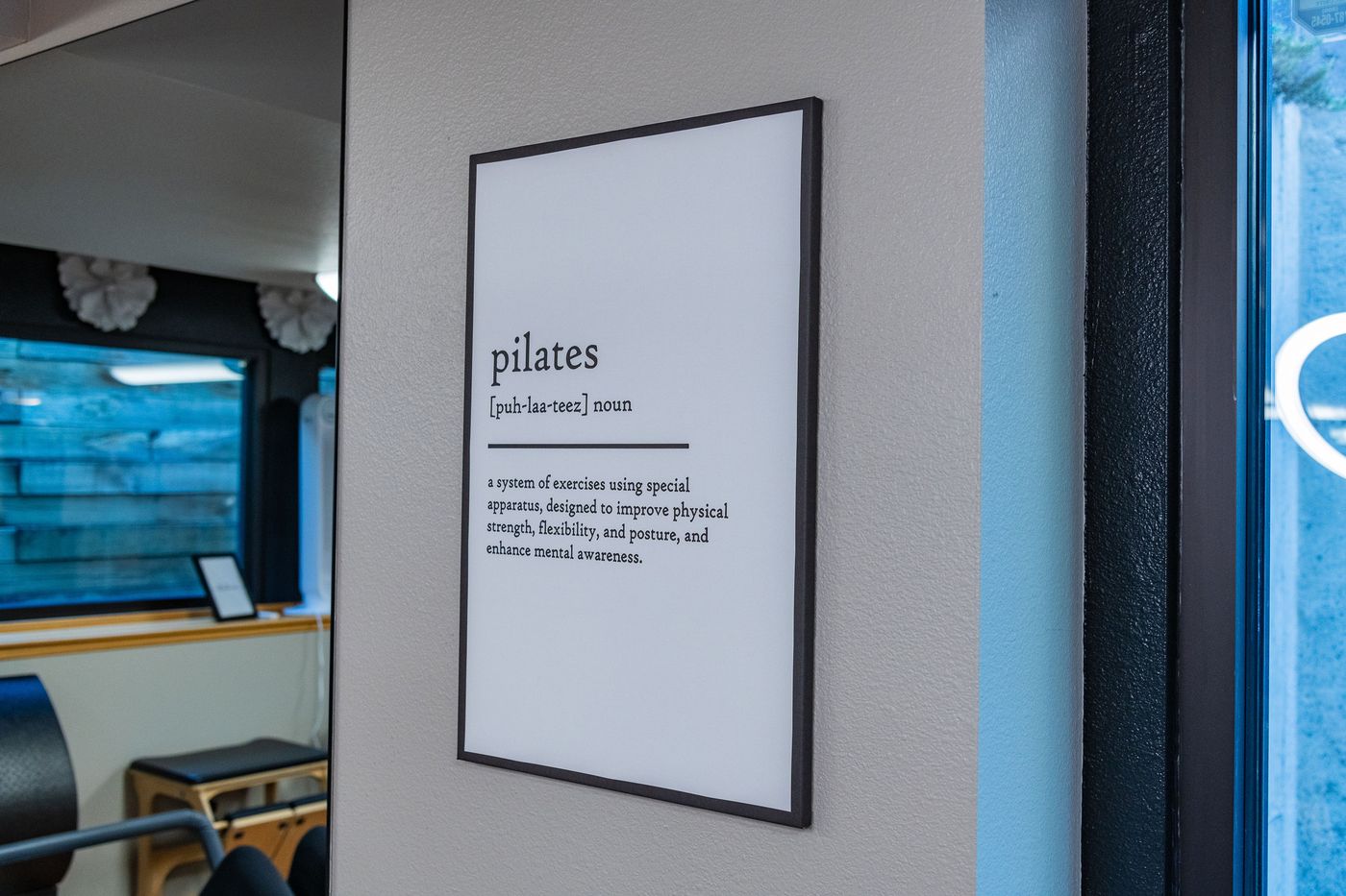 The framed Pilates definition on the studio wall at Core & Crown Collective in Fort Collins