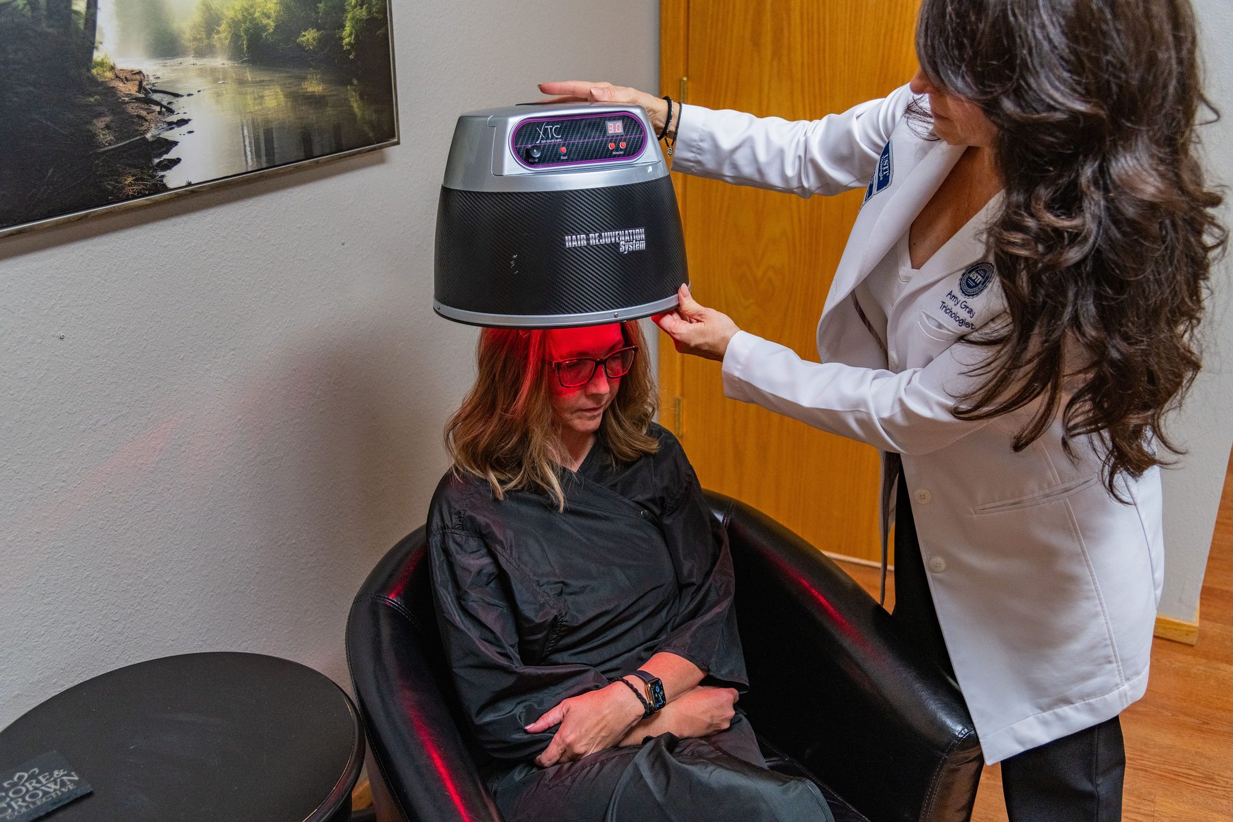 Amy Gray positioning a low-level laser therapy hood over a seated client at Core & Crown Collective in Fort Collins